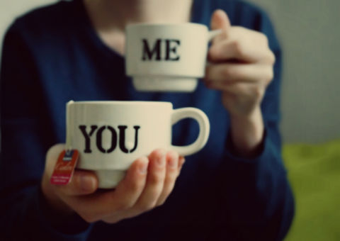 Us and them: how to bridge the gender communication gap: a person holding two mugs with 'me' and 'you' printed on them