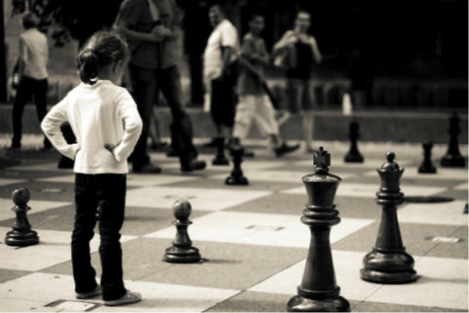 Originators of the future: how to get ahead in banking: a young girl standing on a lifesized chess board